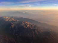 A panoramic view of a mountain range at sunset, with deep shadows and warm golden hues.