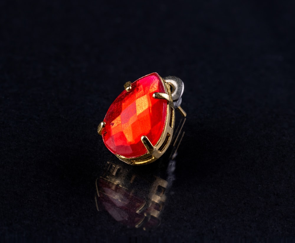 a gold ring with a red stone on a black background