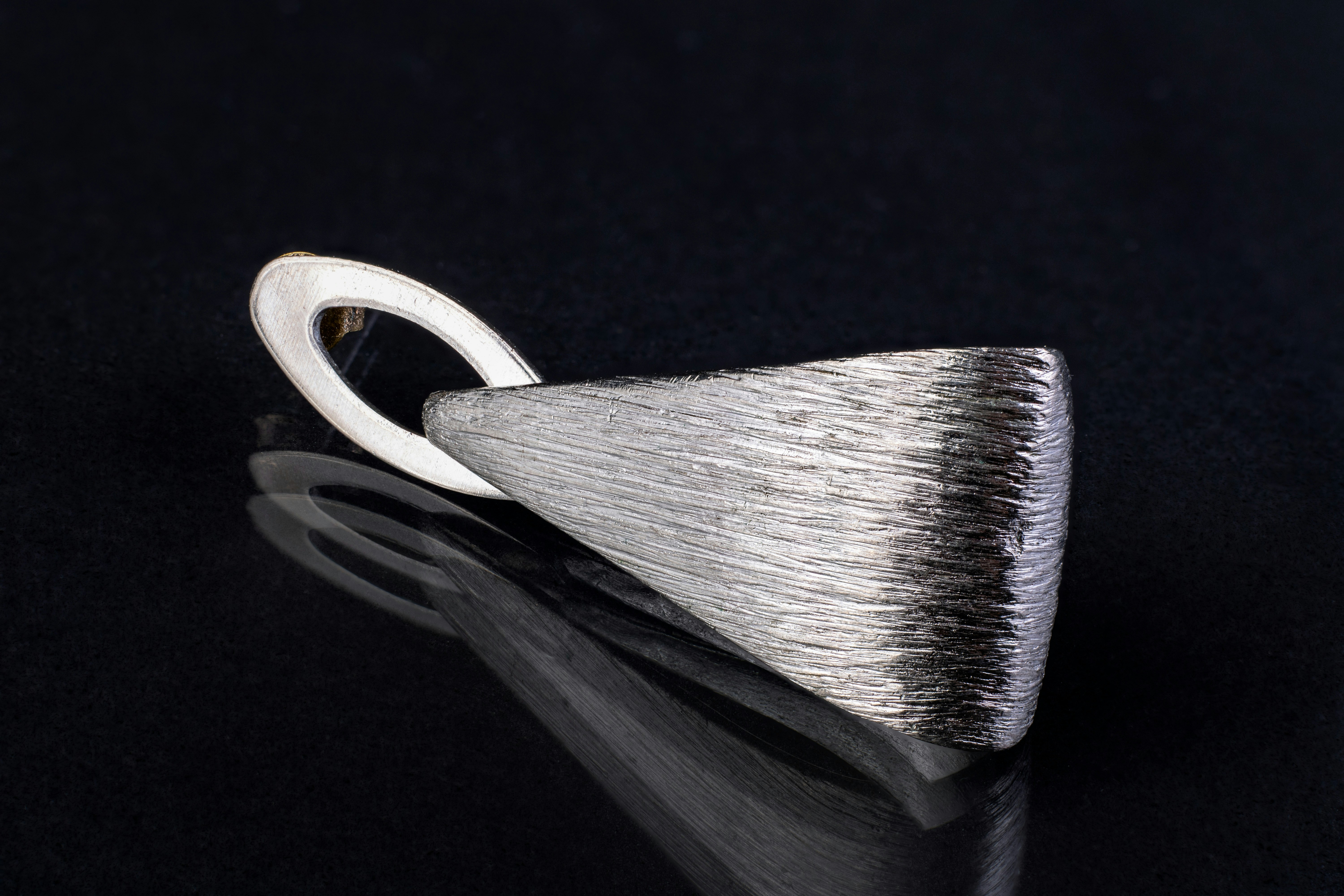 Beautiful silver textured earring on dark reflective surface as background