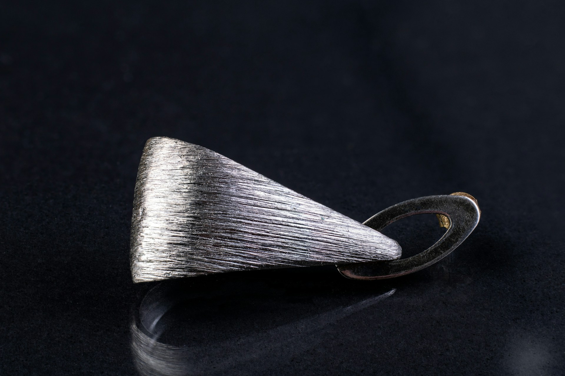 a silver ring with a silver tip on a black surface
