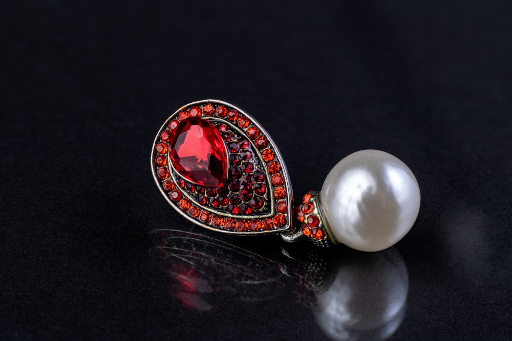a close up of a brooch with a pearl