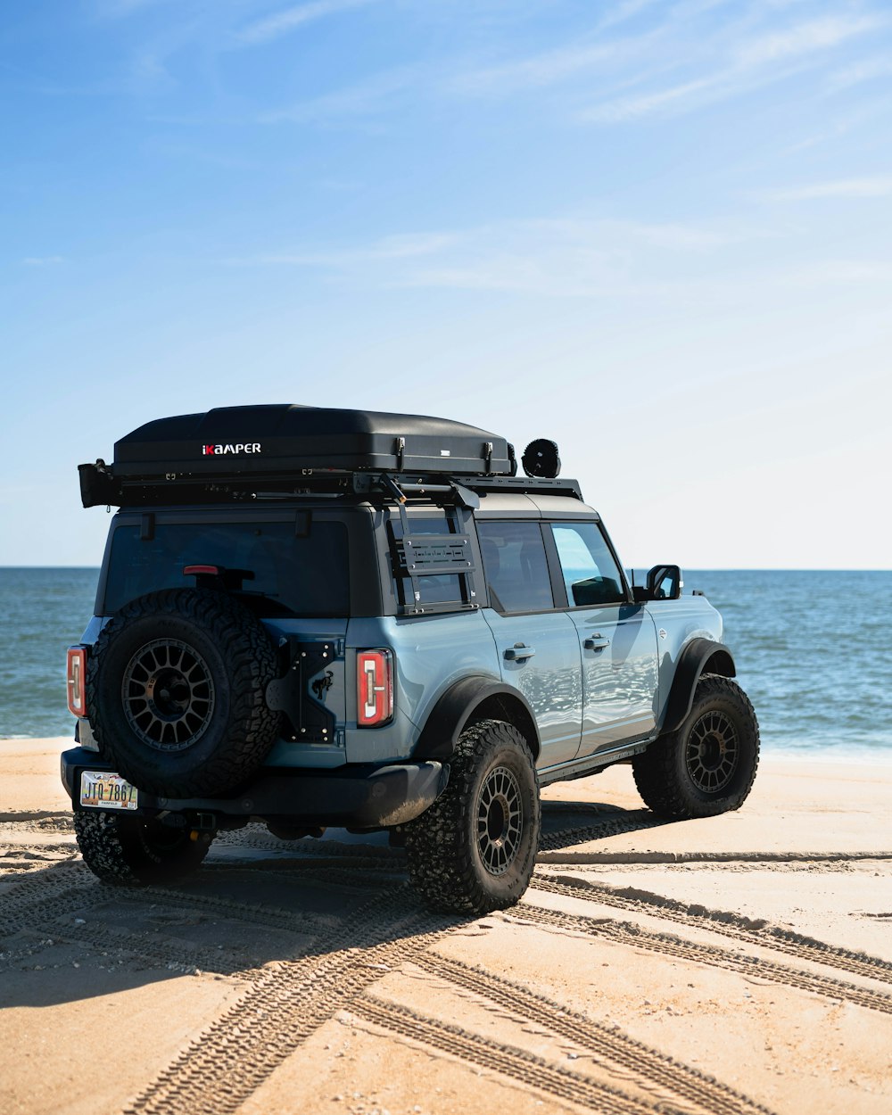 a jeep parked on a beach near the ocean