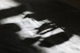 Soft, diffused light creates abstract patterns and shadows on a textured surface, possibly fabric, casting a calming play of light and dark.