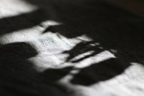 Soft, diffused light creates abstract patterns and shadows on a textured surface, possibly fabric, casting a calming play of light and dark.