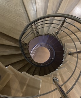 A spiral staircase with wooden steps and metal railings, creating a visually captivating pattern as it descends.