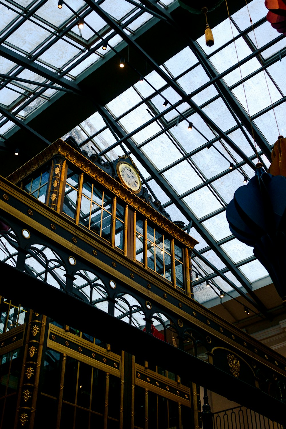 a clock on the side of a building under a glass roof