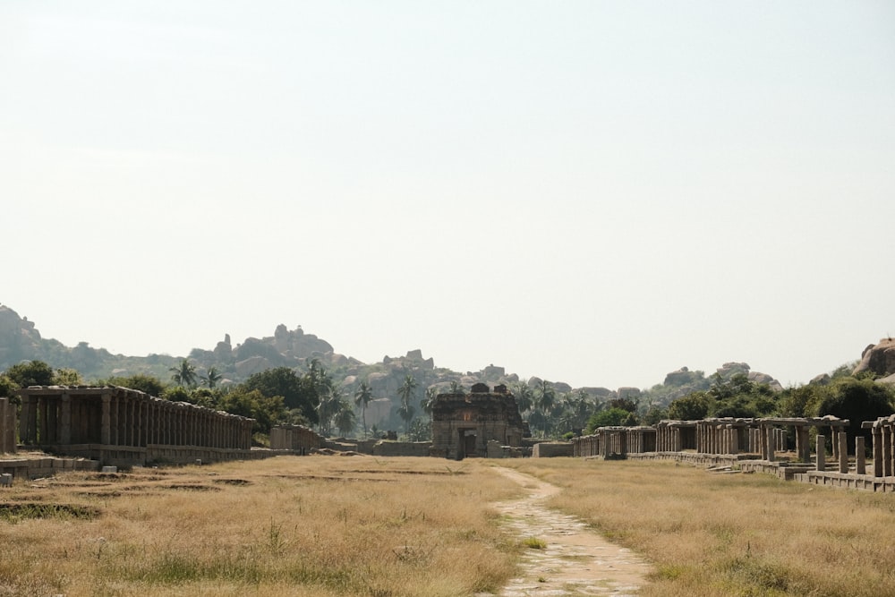 a dirt path in a field next to a stone building