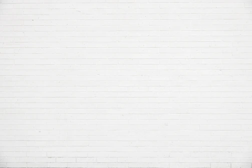 Close-up of a textured white wall with subtle shadows.