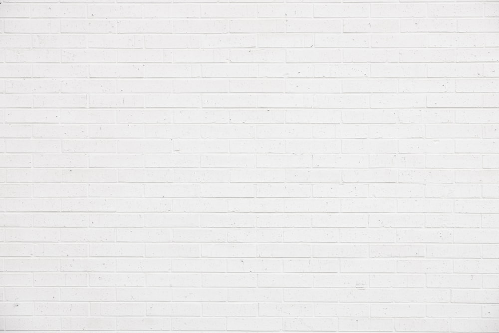 a woman standing in front of a white brick wall
