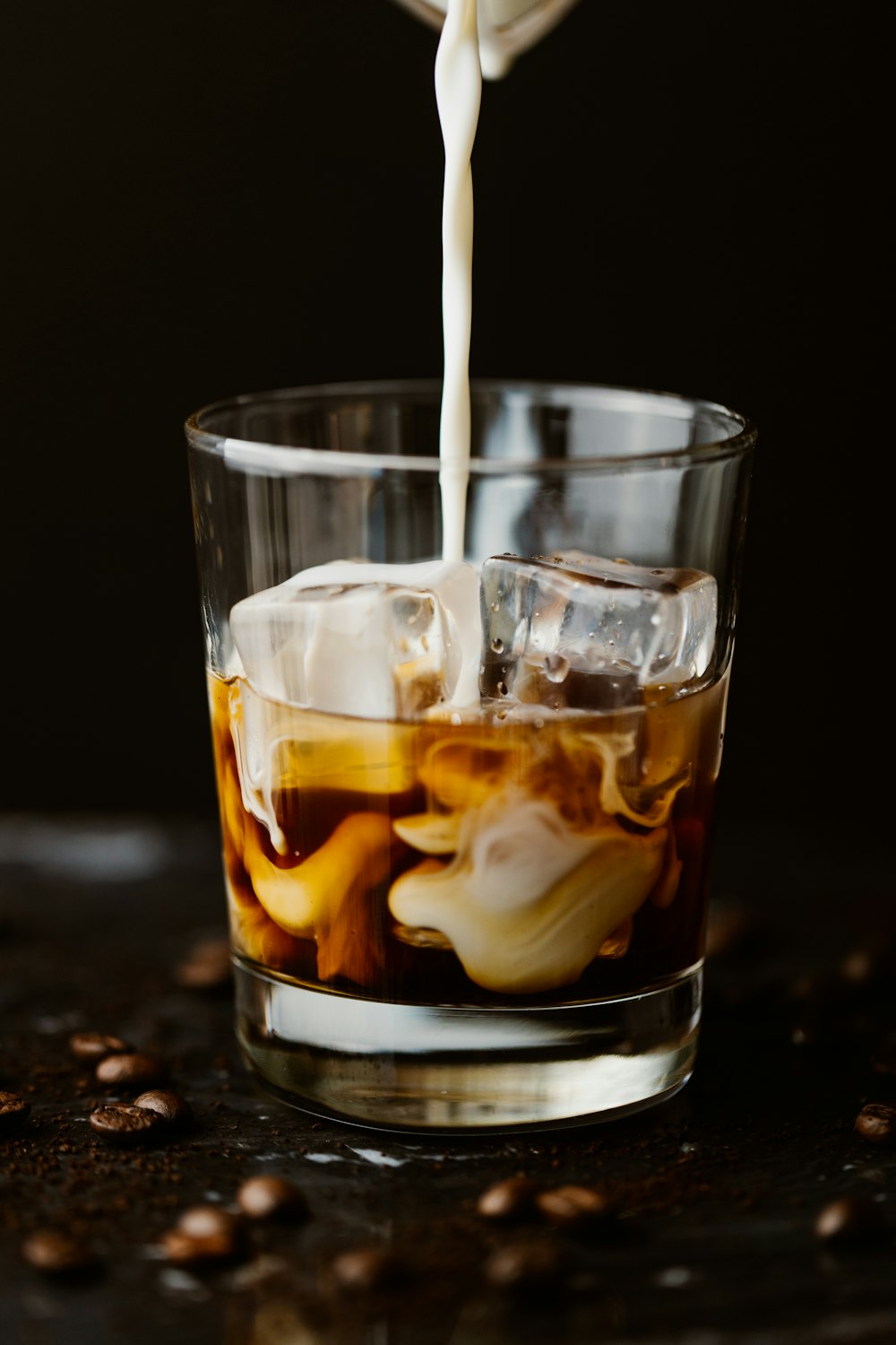 a person pouring coffee into a glass filled with ice