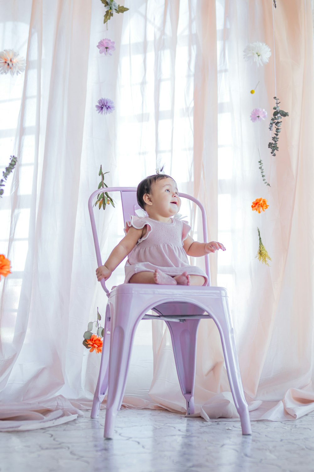 un bébé assis sur une chaise violette devant une fenêtre