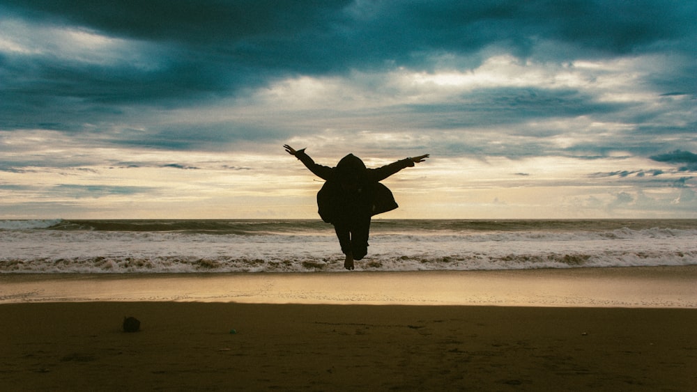 a person jumping in the air on a beach