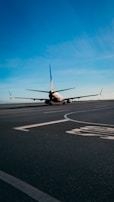 Close-up of a sleek airplane taxiing on the runway under a clear blue sky.