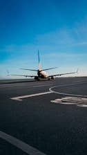 An airplane taxiing on the runway under a clear blue sky.