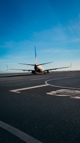 An airplane taxiing on the runway under a clear blue sky.