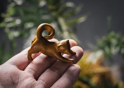 Hand holding a small resin animal figurine with intricate patterns.