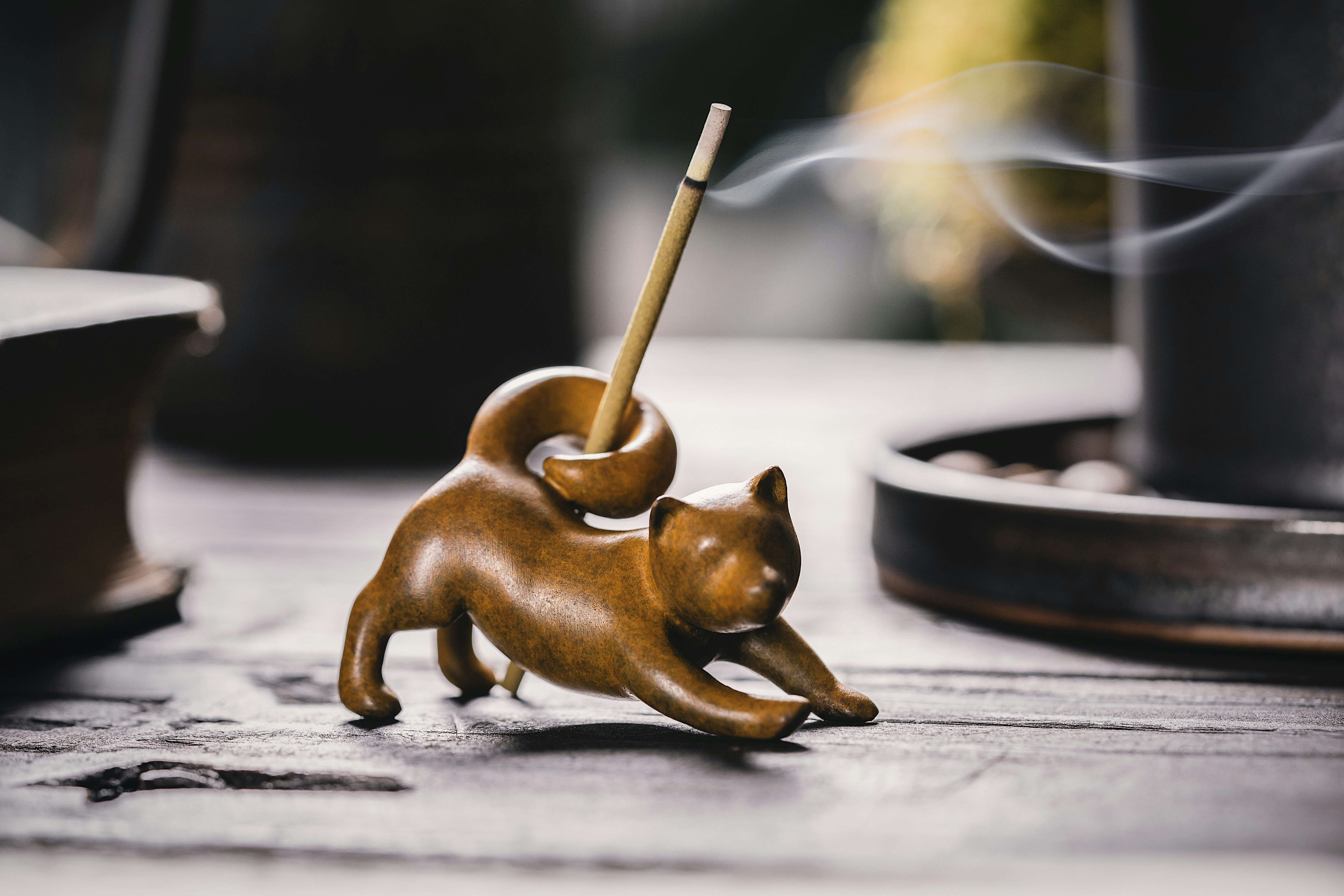 a wooden cat figurine with a bamboo stick in its mouth