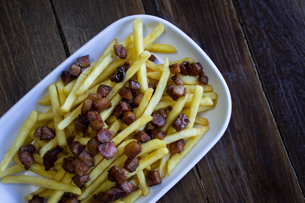 a white plate topped with french fries covered in bacon