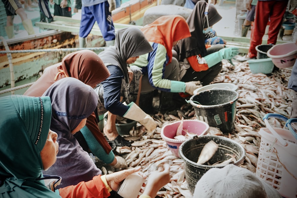 a group of people standing around a pile of fish