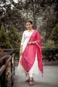 a woman in a white and pink outfit standing on a bridge