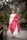 a woman in a white and pink outfit standing on a bridge