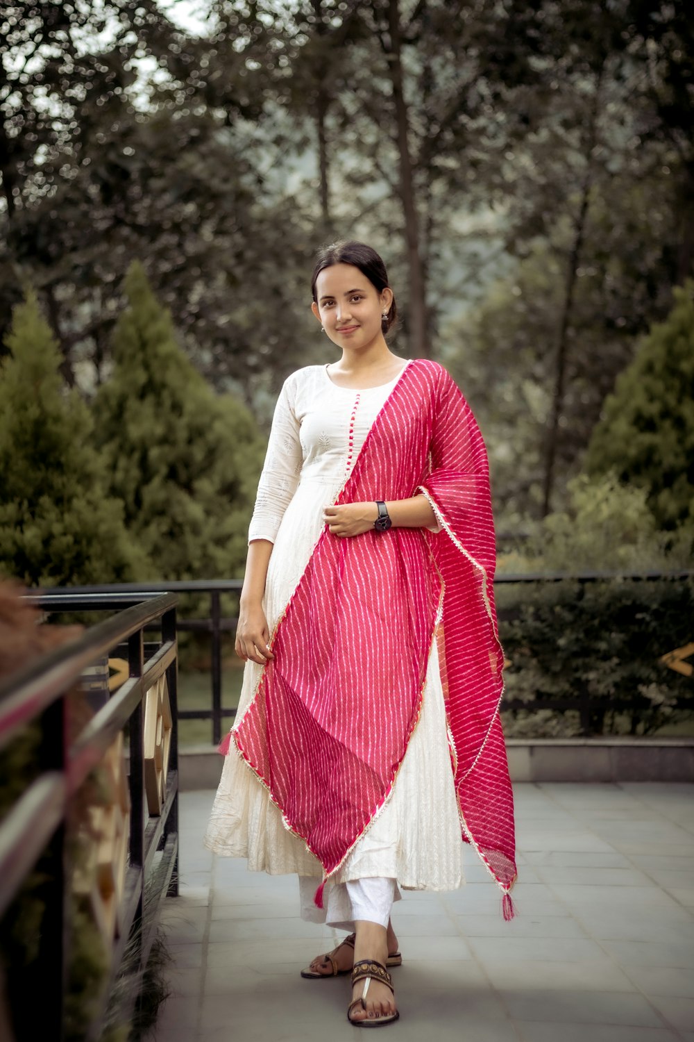 a woman in a white and pink outfit standing on a bridge