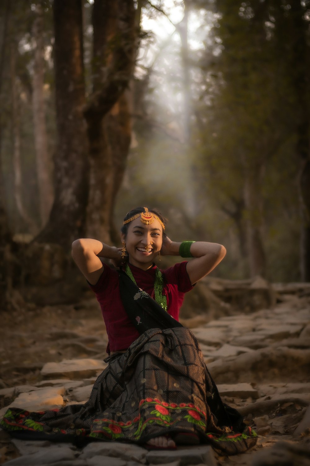 a woman sitting on the ground in a forest