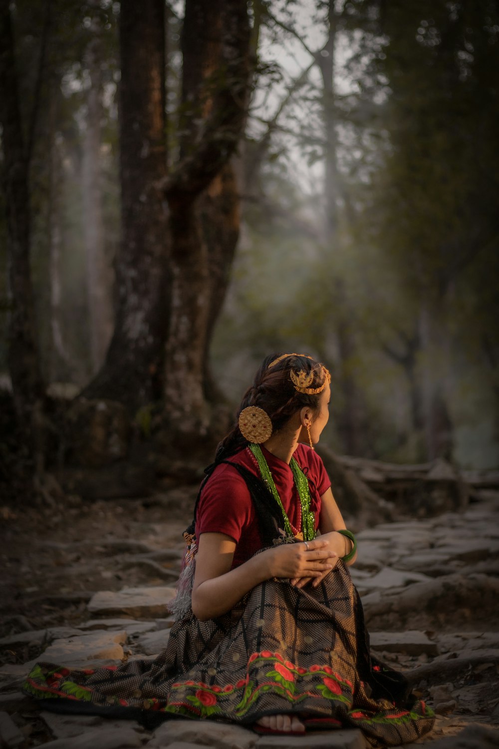 a woman sitting on the ground in a forest