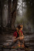 a woman sitting on the ground in a forest