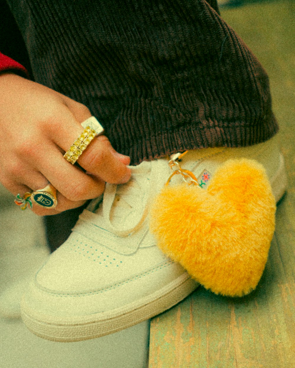 a person wearing a pair of white sneakers and a yellow heart shaped keychain