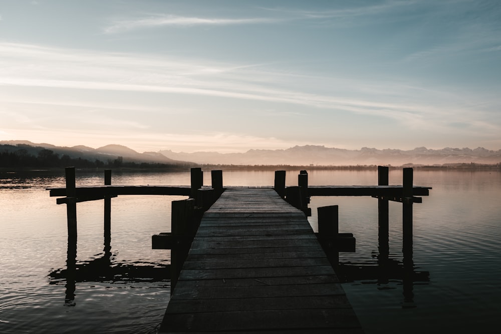 a dock on a lake with mountains in the background