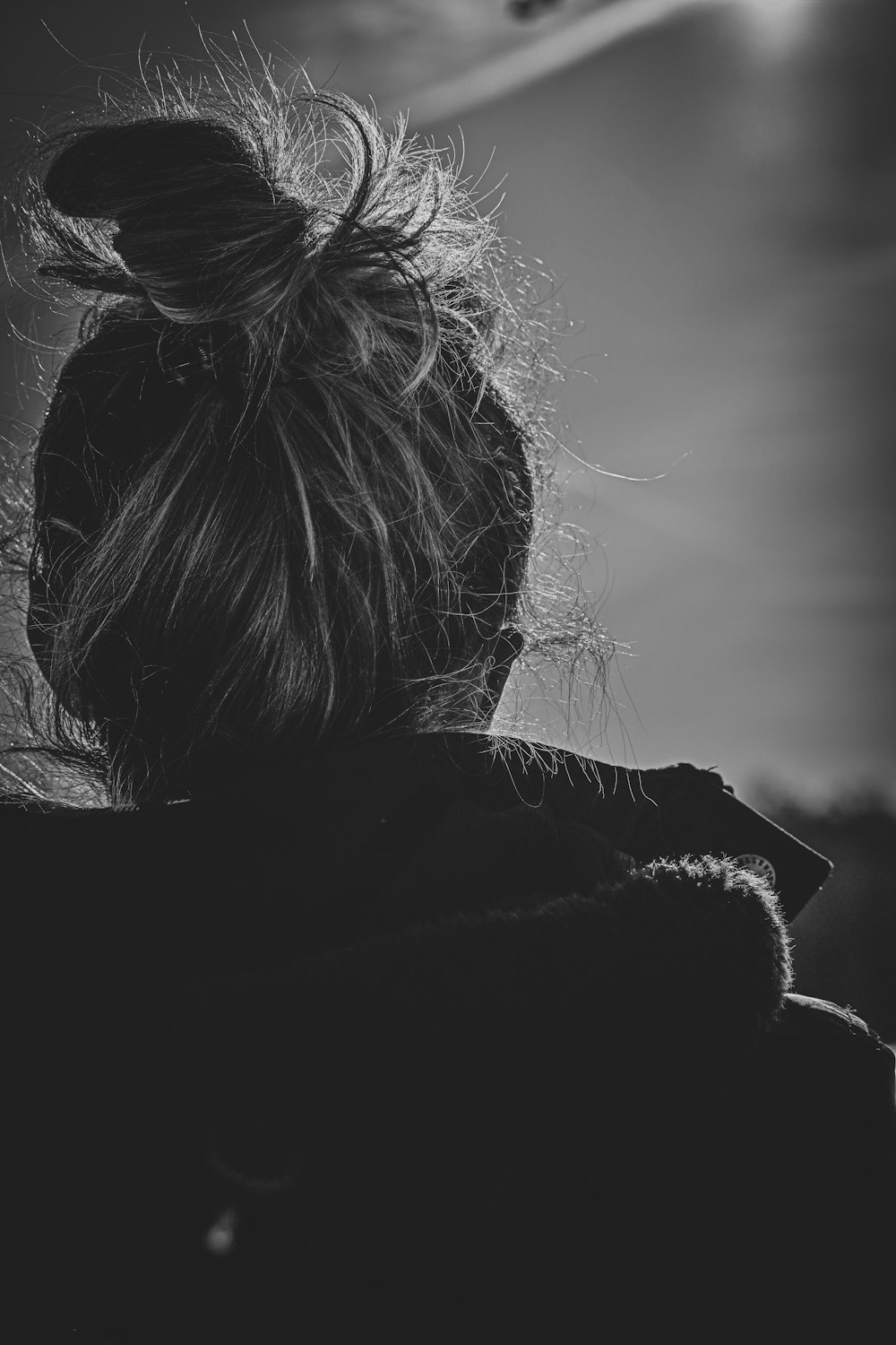 a black and white photo of a woman with her hair in a bun