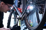 A mechanic tuning a bike’s gears with focused attention in the service area.