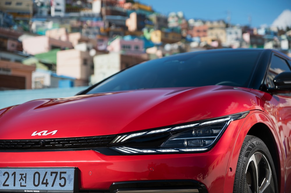 a red car parked in front of a city