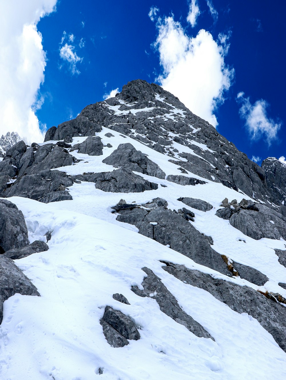 a snow covered mountain under a blue sky with clouds