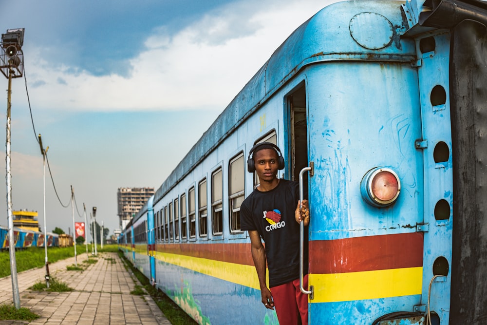 a man standing on the side of a blue train