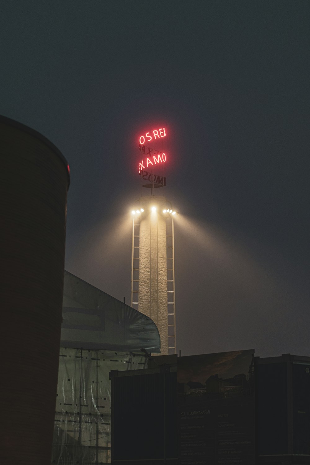 a tall tower with a neon sign on top of it