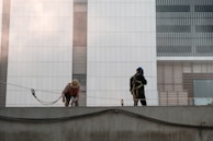 Workers applying finishing touches to a building facade with safety gear.