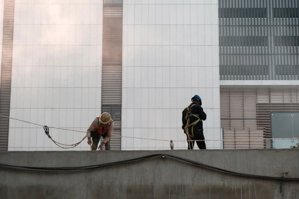 Modern building facade under renovation with workers using safety harnesses.