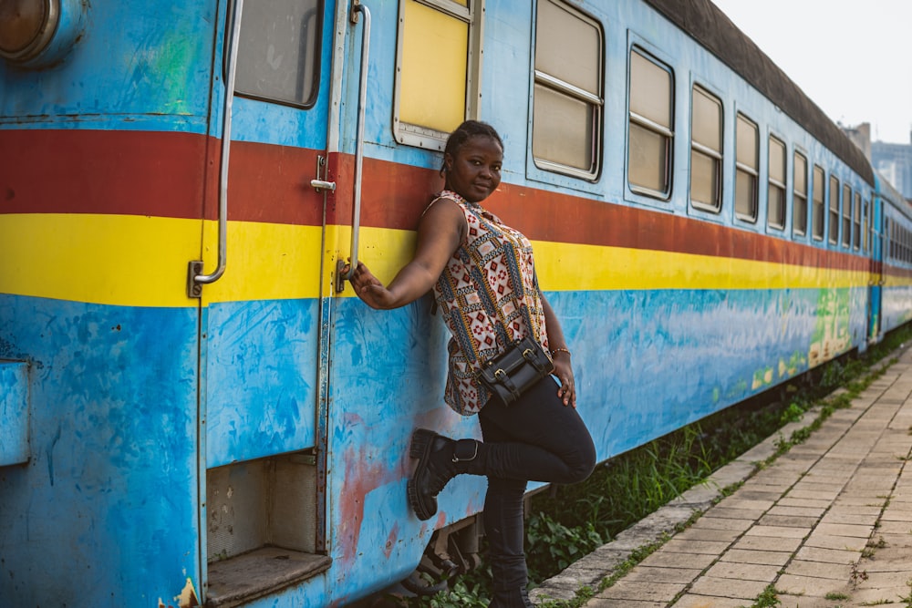 a woman leaning against a blue and yellow train