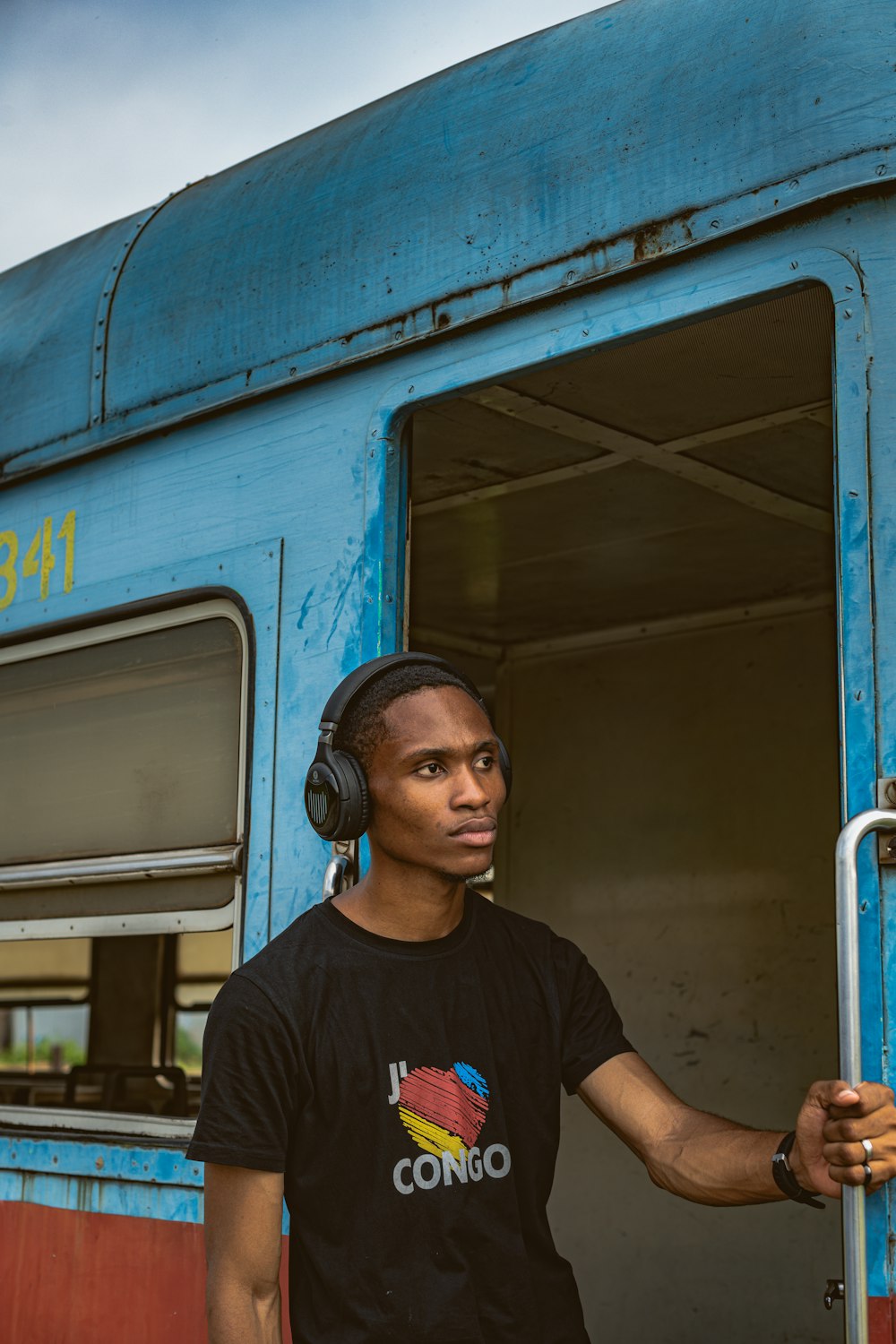 a man with headphones standing in the doorway of a train
