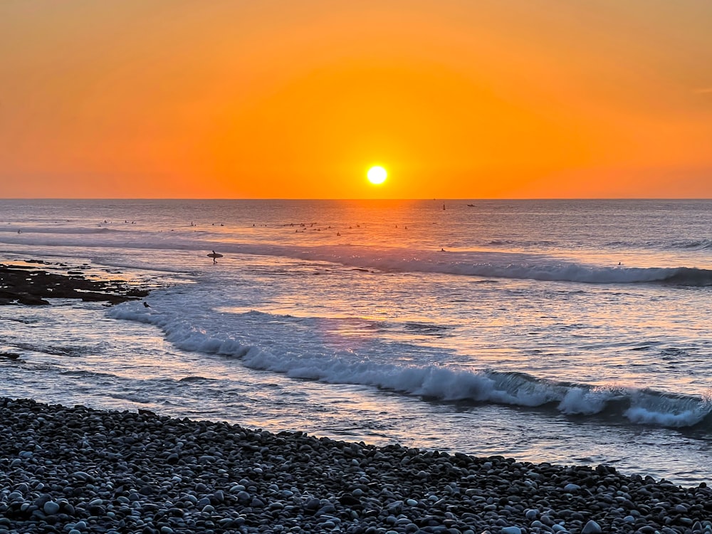 Un tramonto sull'oceano con un surfista nell'acqua