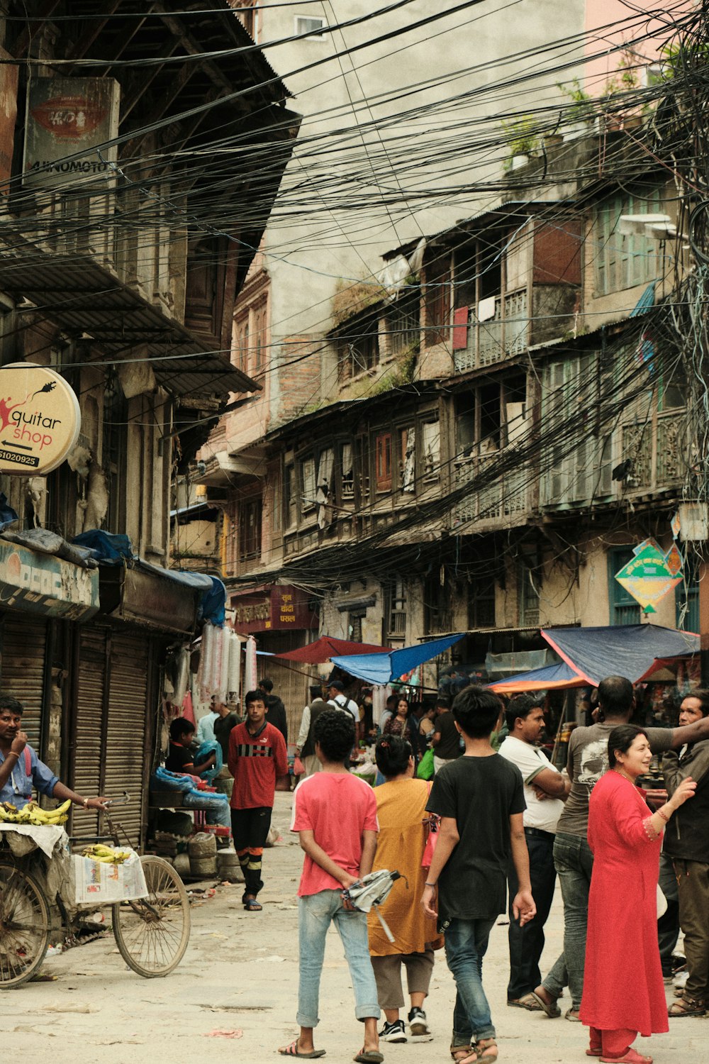 a group of people walking down a street next to tall buildings