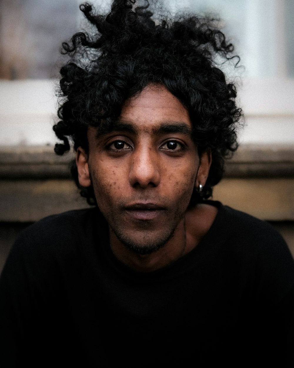 a man with curly hair is looking at the camera