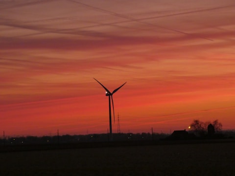A wind turbine standing tall against a sunset backdrop.