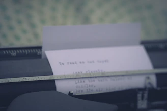 Close-up of a typewriter with a sheet of paper halfway typed, purple and gold light filtering in.