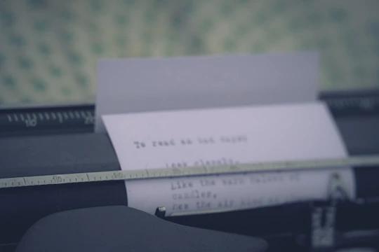 Close-up of a typewriter with a sheet of paper halfway typed, purple and gold light filtering in.