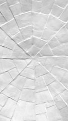 A close-up view of a paper surface featuring a radial geometric pattern with numerous folds and creases converging towards the center.