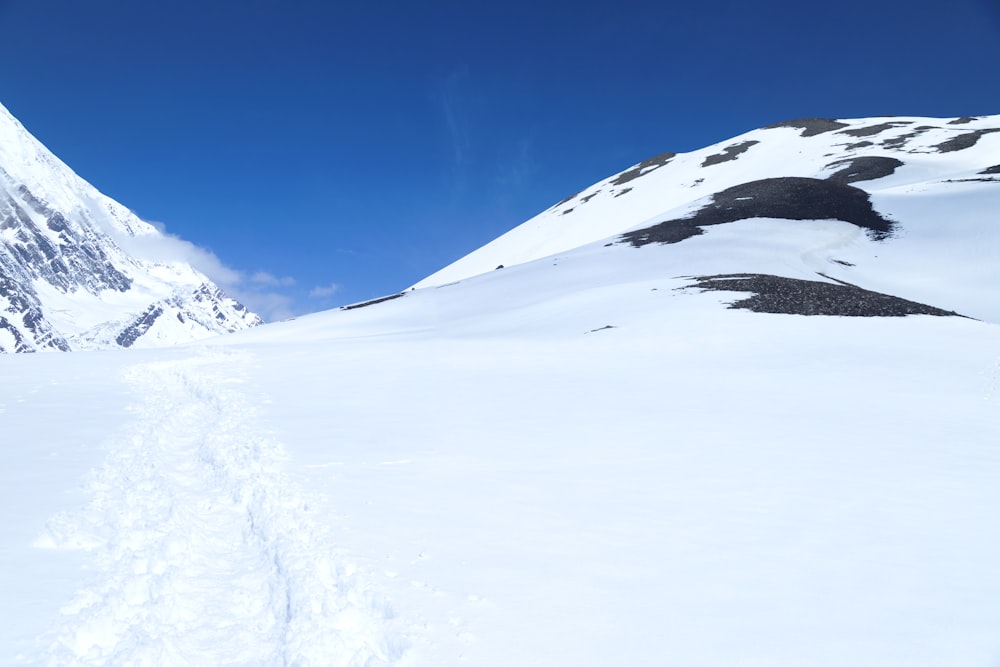 a snow covered mountain with tracks in the snow