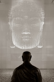A serene monk meditating in front of a softly glowing screen displaying Buddha Dhamma teachings.